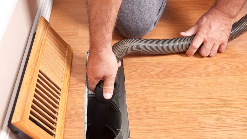 A man cleaning the air duct using vacuum
